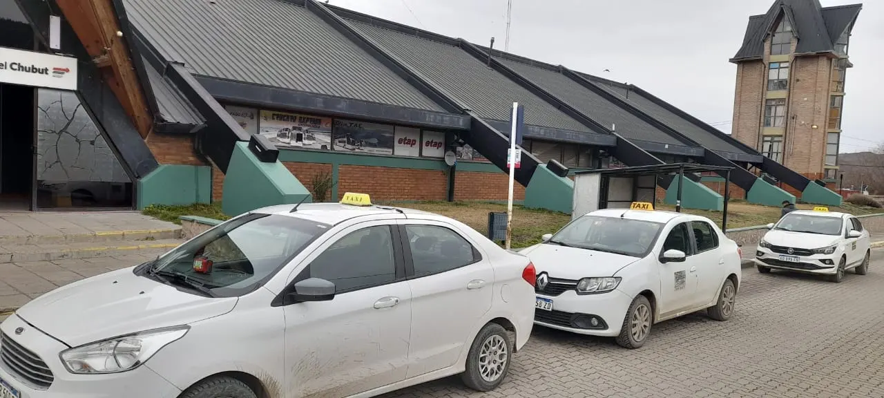 Tres taxis blancos esperando frente a la terminal de Esquel